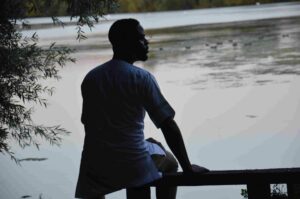 a man sitting on a bench by water