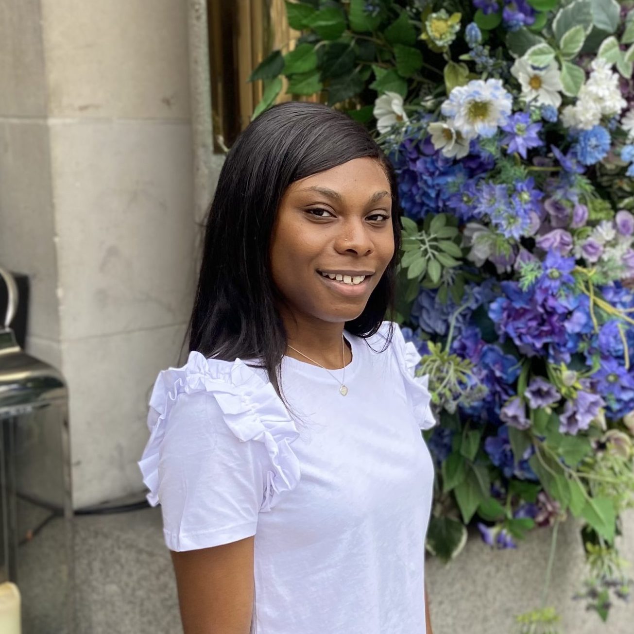 A person smiling in front of a flower display