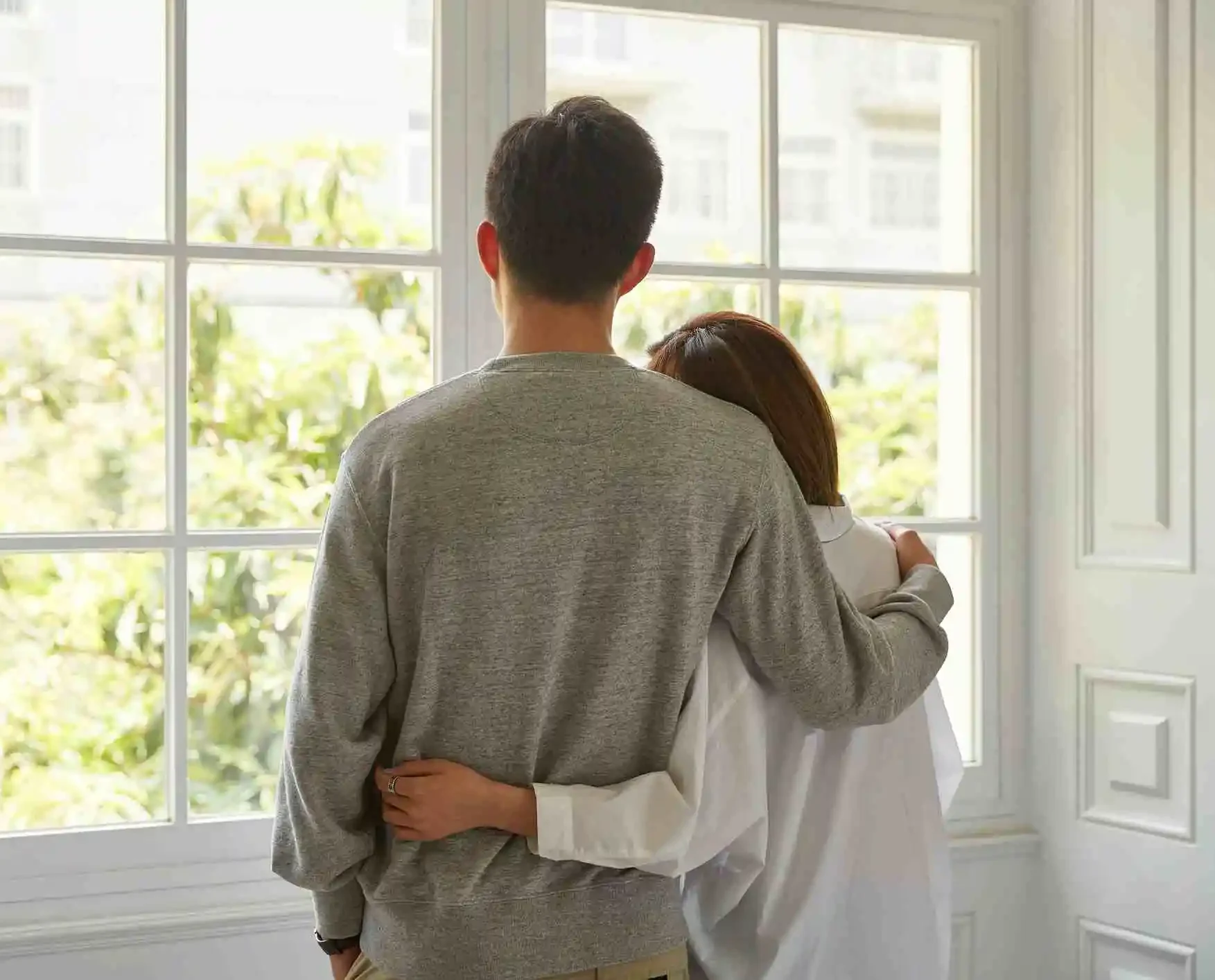 rear view of a young asian couple looking out of window during staying at home order