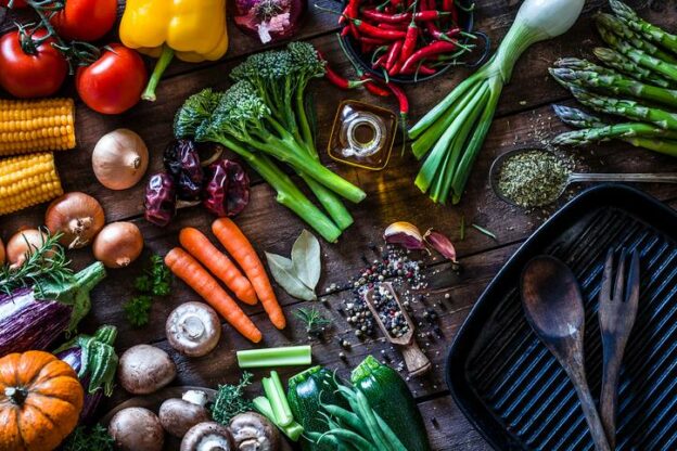 Top view of a rustic wooden table filled with fresh organic vegetables ready for cooking.
