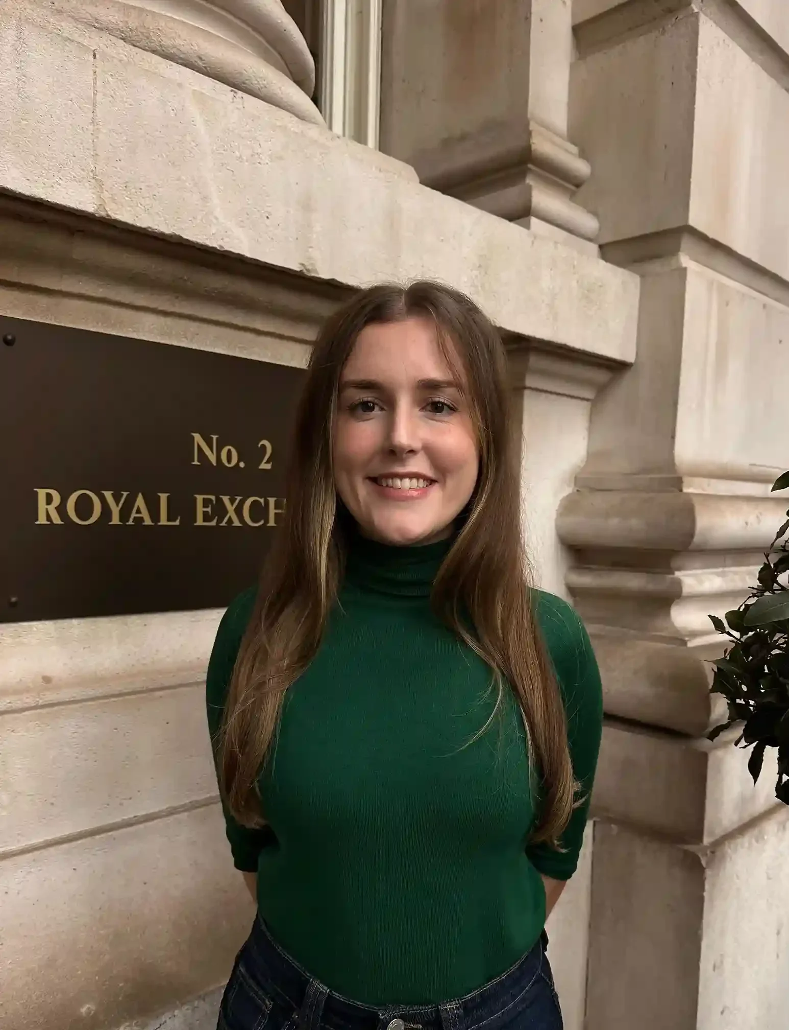 A woman smiling in green turtle neck