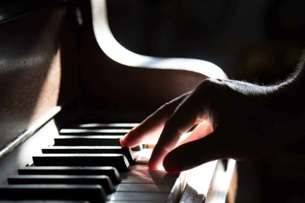 A close-up of a hand playing a piano