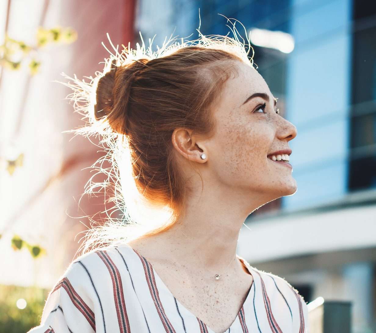 A person smiling with her hair pulled back