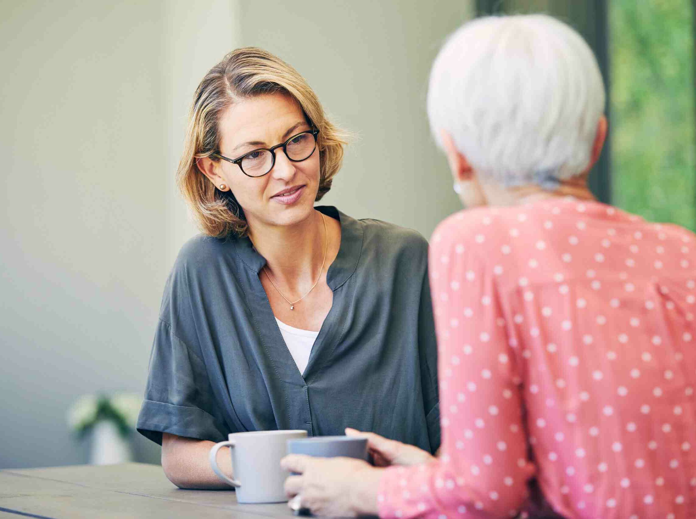 Two women sitting at a table having a hot drink and catching up