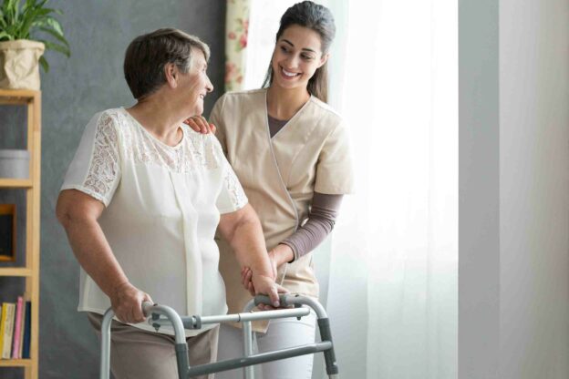 A nurse helping an older woman with a walker