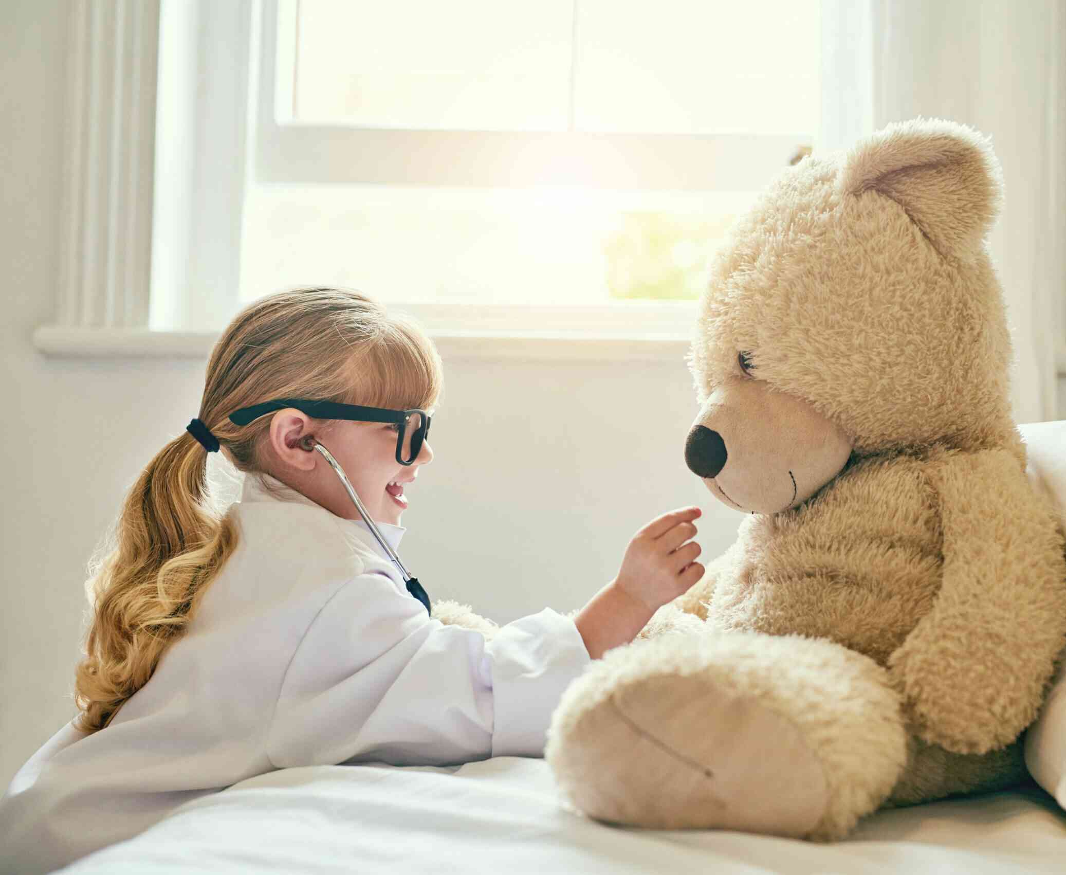 A child playing doctor with a teddy bear