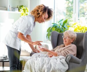 Nurse giving a patient her medication sitting in a chair