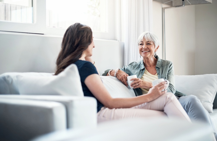 Shot of an elderly woman and her daughter having a chat over coffee on the sofa at home