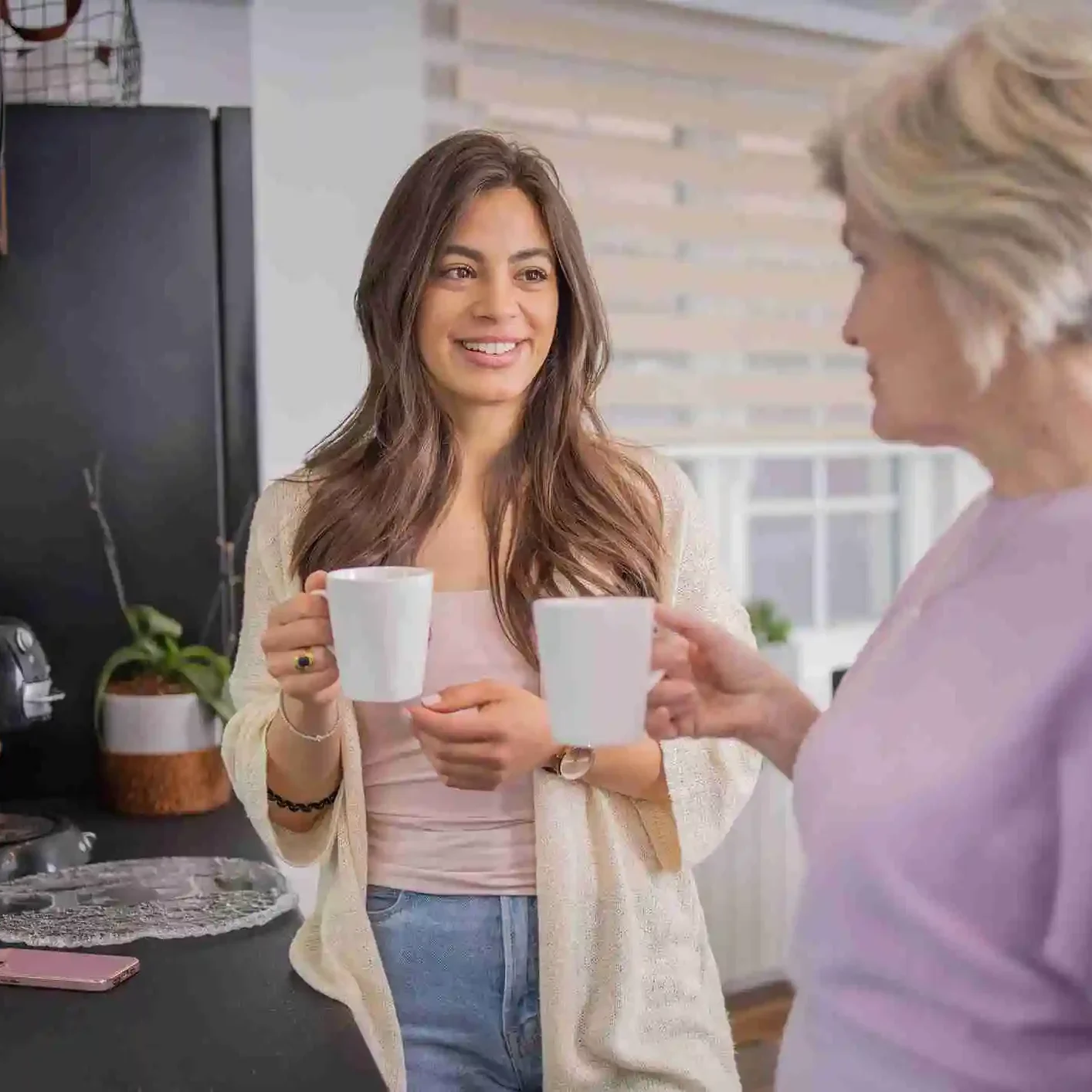 2 females in a kitchen drinking tea