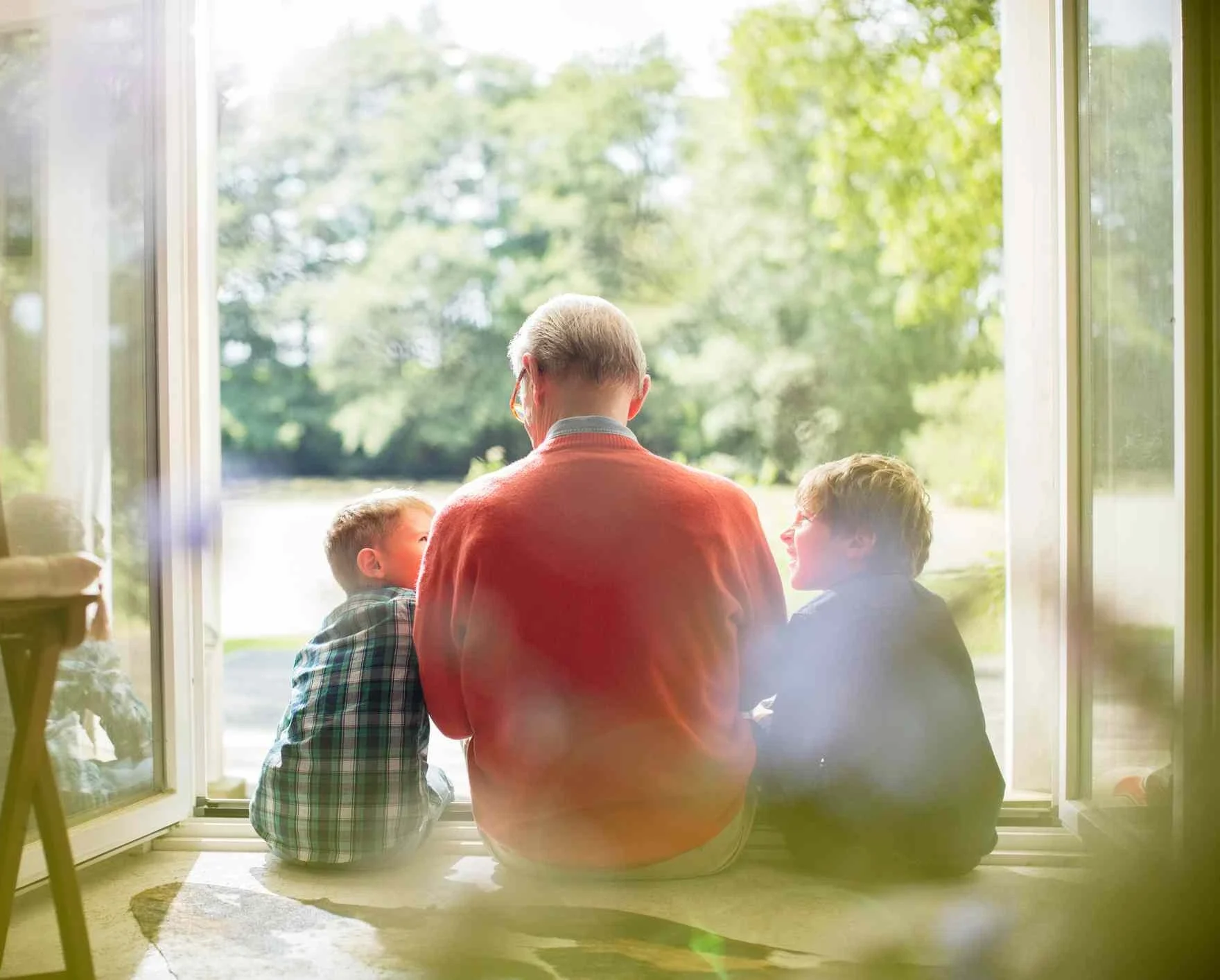 Grandfather and 2 small children looking outside