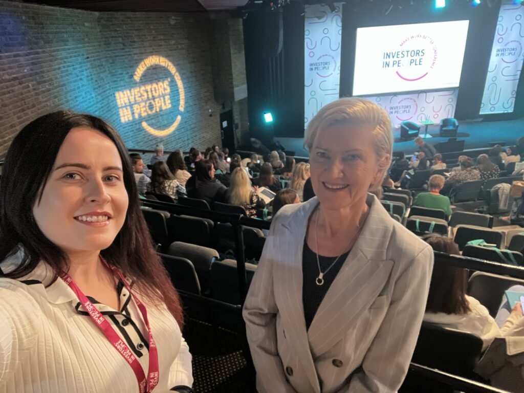 2 women in front of audience looking at a stage