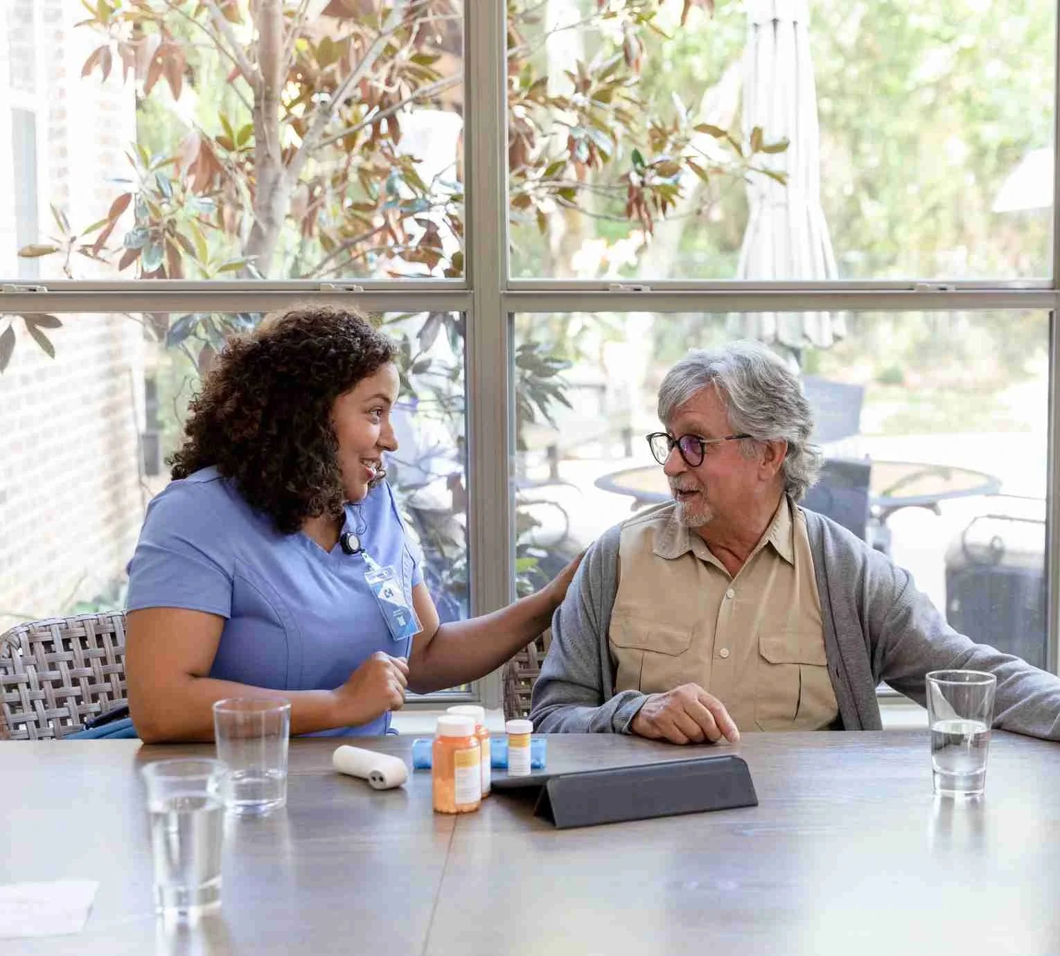 Nurse and elderly man discussing medication at kitchen table
